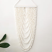 Coastal shell wall hanging featuring 9 cascading strands, designed to bring natural texture and relaxed boho style into your home. Measuring 105cm long x 40cm wide, this lightweight statement piece is perfect for styling in living rooms, bedrooms or entryways.