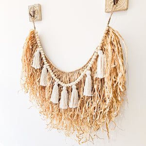 Natural straw, Raffia hanging with wood beaded garland of cotton tassels. Coastal Bohemain, boho inspired home. Coastal boho interior style wall hangings. Natural wall art. Natural earrhy organic materials. 